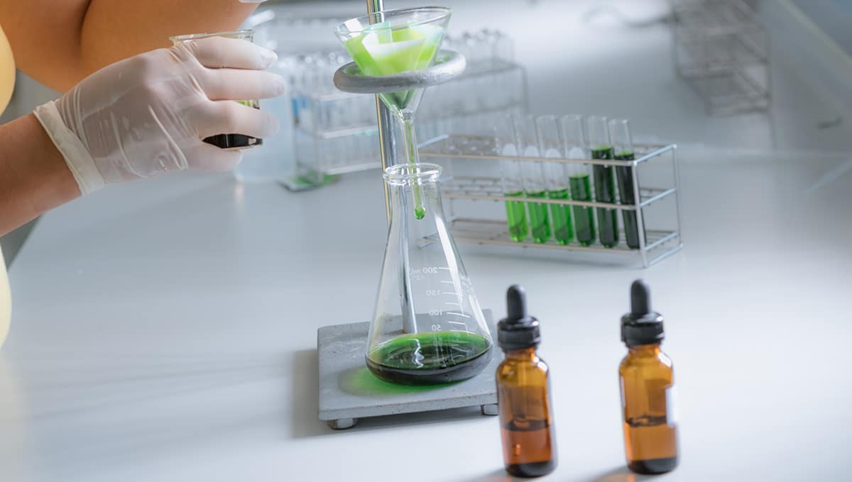 a person pouring green liquid into a beaker